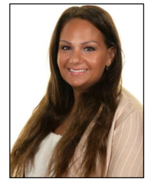 A picture of the headteacher smiling. She is a white female with long brown hair, wearing a light pink blazer